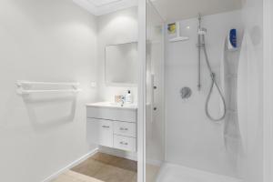 a white bathroom with a shower and a sink at Sun, Sand, Serenity - Waihi Beach Holiday Home in Waihi Beach +30 photos