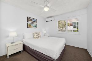 a white bedroom with a bed and a nightstand at Surfers Paradise- meters from the beach! in Gold Coast