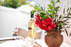 a vase with red flowers on a table with a bottle of wine at Margarita Studios in Parikia
