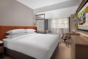 a hotel room with a large white bed and a desk at Home2 Suite by Hilton Harbin Central Street in Harbin