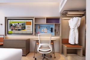 a room with a chair and a dress hanging on a wall at Home2 Suite by Hilton Harbin Central Street in Harbin