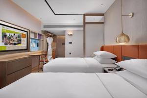 a hotel room with two beds and a tv at Home2 Suite by Hilton Harbin Central Street in Harbin