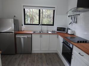 una cucina con mobili bianchi, un lavandino e una finestra di Halls Gap Cottages a Halls Gap Altre 5 foto