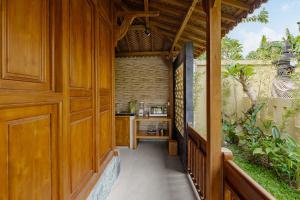 an outdoor hallway with wood paneling and a wooden door at Suraya Ubud Villa in Ubud