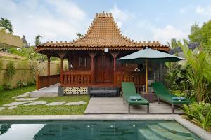 a gazebo with chairs and an umbrella next to a pool at Suraya Ubud Villa in Ubud