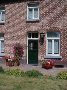 um edifício de tijolos com uma porta verde e flores em Hoeve Heidonk em Horn