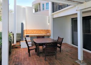 un patio con mesa, sillas y banco en Sandcastles 1 - Beach front, en Bargara