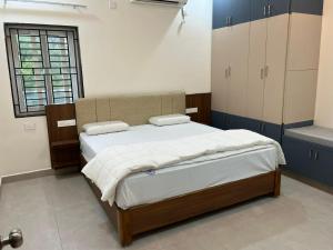a bedroom with a bed with white sheets and a window at Achyuta Homestay in Tirupati