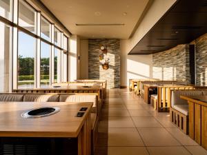 a restaurant with wooden tables and benches and windows at The Orion Hotel Motobu Resort & Spa in Motobu