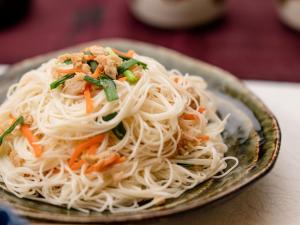 a plate of noodles with vegetables on a table at The Orion Hotel Motobu Resort & Spa in Motobu