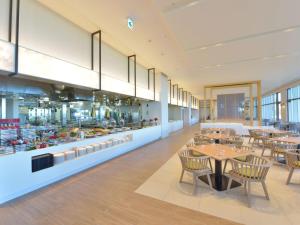 a restaurant with tables and chairs and a kitchen at The Orion Hotel Motobu Resort & Spa in Motobu