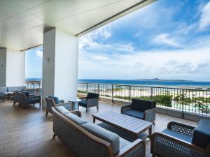 a balcony with chairs and tables and a view of the ocean at The Orion Hotel Motobu Resort & Spa in Motobu