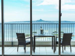 a balcony with a table and chairs and the ocean at The Orion Hotel Motobu Resort & Spa in Motobu