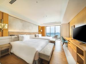 a hotel room with two beds and a flat screen tv at The Orion Hotel Motobu Resort & Spa in Motobu