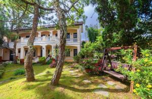 an exterior view of a large house with trees at Villa Trung Nghĩa 16 in Da Lat