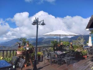 una terraza con mesas, sillas y sombrilla en Victoria Peak Garden Suburb, en Renai