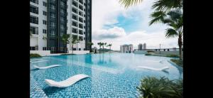 a swimming pool with white chairs in a building at Humaira - Metropol in Bukit Mertajam
