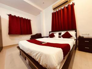 a bedroom with a large bed with red curtains at Silver Key Suites in Nagpur +8 photos