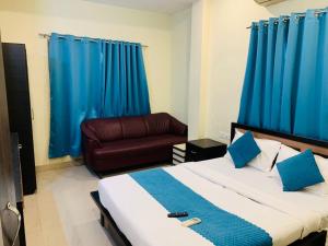 a bedroom with a bed and a couch and blue curtains at Silver Key Suites in Nagpur