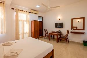 a bedroom with a bed and a table and a television at Abhayawewa Resort in Anuradhapura