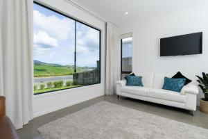 een woonkamer met een bank en een groot raam bij Karioi Mountain View in Raglan