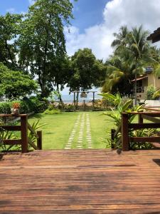 una terraza de madera con vistas a un campo de césped en Pousada Iyalodê, en Maraú