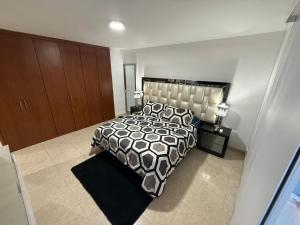 a bedroom with a bed with a black and white comforter at Apartamento de Lujo in Floridablanca +9 photos