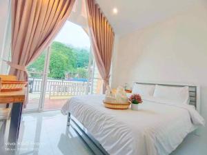 a bedroom with a white bed with a large window at ไวท์เฮาส์ ภูชี้ฟ้า in Ban Tin Pet