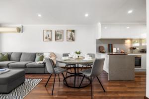 a kitchen and a living room with a table and chairs at Tranquil Suite - Modern Comfort between CBD & Beach in Thebarton
