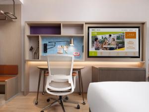 a desk with a chair and a tv on a wall at Home2 Suite by Hilton Harbin Central Street in Harbin