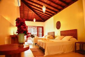 a bedroom with two beds and a table with roses at Pousada Iyalodê in Marau