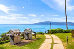 two barbecue equipment next to a path next to the ocean at Kuleana Club #510 - Ocean View -1 bedroom & 1 bathroom - 2nd Floor in Kahana