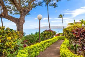 a path through a garden with flowers and a street light at Kuleana Club #510 - Ocean View -1 bedroom & 1 bathroom - 2nd Floor in Kahana