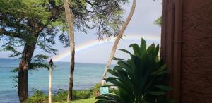 a rainbow over the ocean from a room with a window at Kuleana Club #510 - Ocean View -1 bedroom & 1 bathroom - 2nd Floor in Kahana