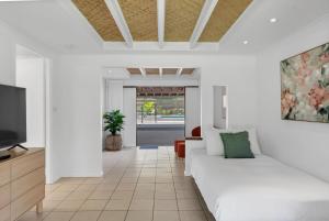 a white living room with a couch and a tv at Belle Escapes Endeavour To Impress in Clifton Beach
