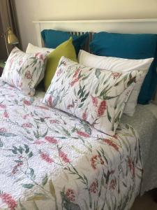 a bed with two pillows and a floral blanket at Cosy Golf Course Retreat in Tamborine Mountain with Wifi & Aircon in Mount Tamborine