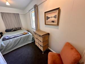a bedroom with a bed and a chair and a window at Alpine House, Holiday Home, Sleeps 6, Super Cosy, 4 beds in Otira