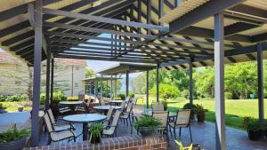 een terras met tafels en stoelen onder een houten pergola bij Mary MacKillop Spirituality Centre Central Coast in Kincumber South