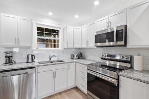 a white kitchen with white cabinets and stainless steel appliances at Wood House King Bd 2 Queens Fire Pit in St. John's +16 photos