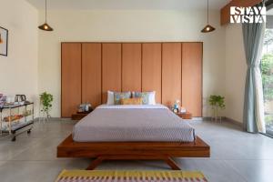 a bedroom with a large bed with a wooden headboard at The Den by Vieda - Part of StayVista in Karjat +51 photos