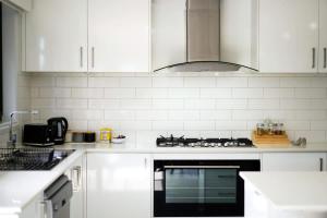 a kitchen with white cabinets and a stove top oven at Ramlegh Spring Estate - High Quality Family Living in Clyde North