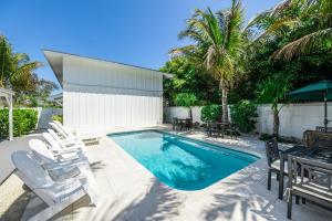 a swimming pool with chairs and a table at Barefoot by the Bay at Bayside Bungalow in Anna Maria