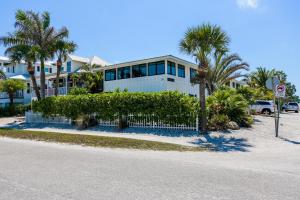 a house with palm trees in front of a street at Barefoot by the Bay at Bayside Bungalow in Anna Maria