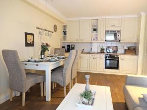eine Küche mit weißen Schränken und einem Tisch und Stühlen in der Unterkunft Kampstraße 9, W2, GB3 in Westerland