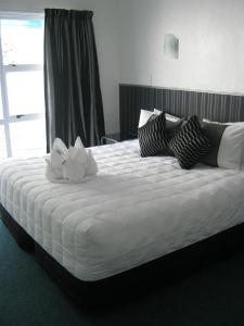 Palm Court Motor Inn في روتوروا: سرير كبير عليه وردتين بيضاء