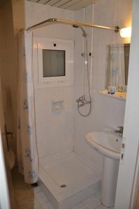 a white bathroom with a shower and a sink at Hotel Exarchion in Athens