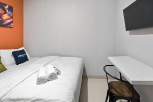 a white bed with towels on it next to a desk at Urbanview Green Lake Sunter Residence in Jakarta +16 photos