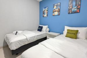 two beds in a room with blue walls at Urbanview Green Lake Sunter Residence in Jakarta
