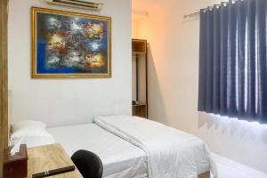 a room with a bed and a painting on the wall at Urbanview Hotel Rimadi Slipi in Jakarta