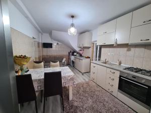 a kitchen with white cabinets and a table with chairs at Guesthouse Citycenter in Craiova